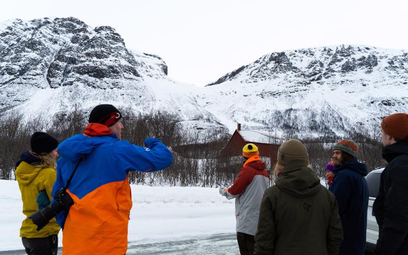 Mange studenter og lærer foran bratte fjell, på snøskredkurs i Breivikeidet.